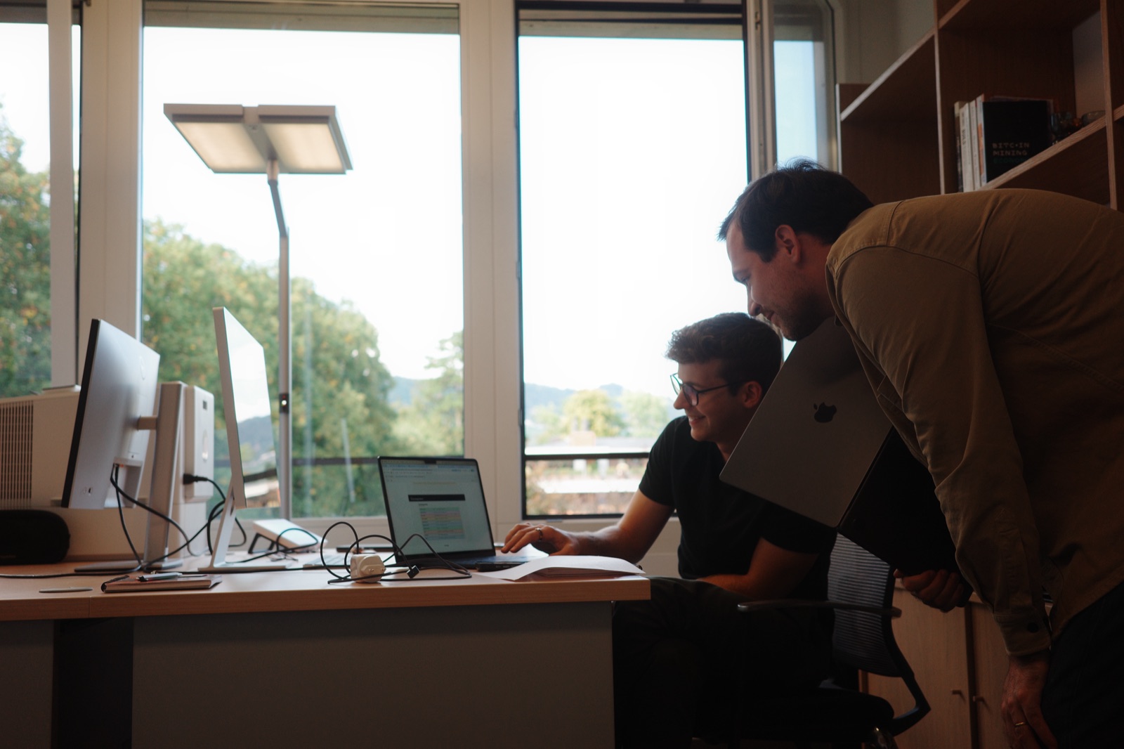Two of us at a desk, laughing at something on a laptop.