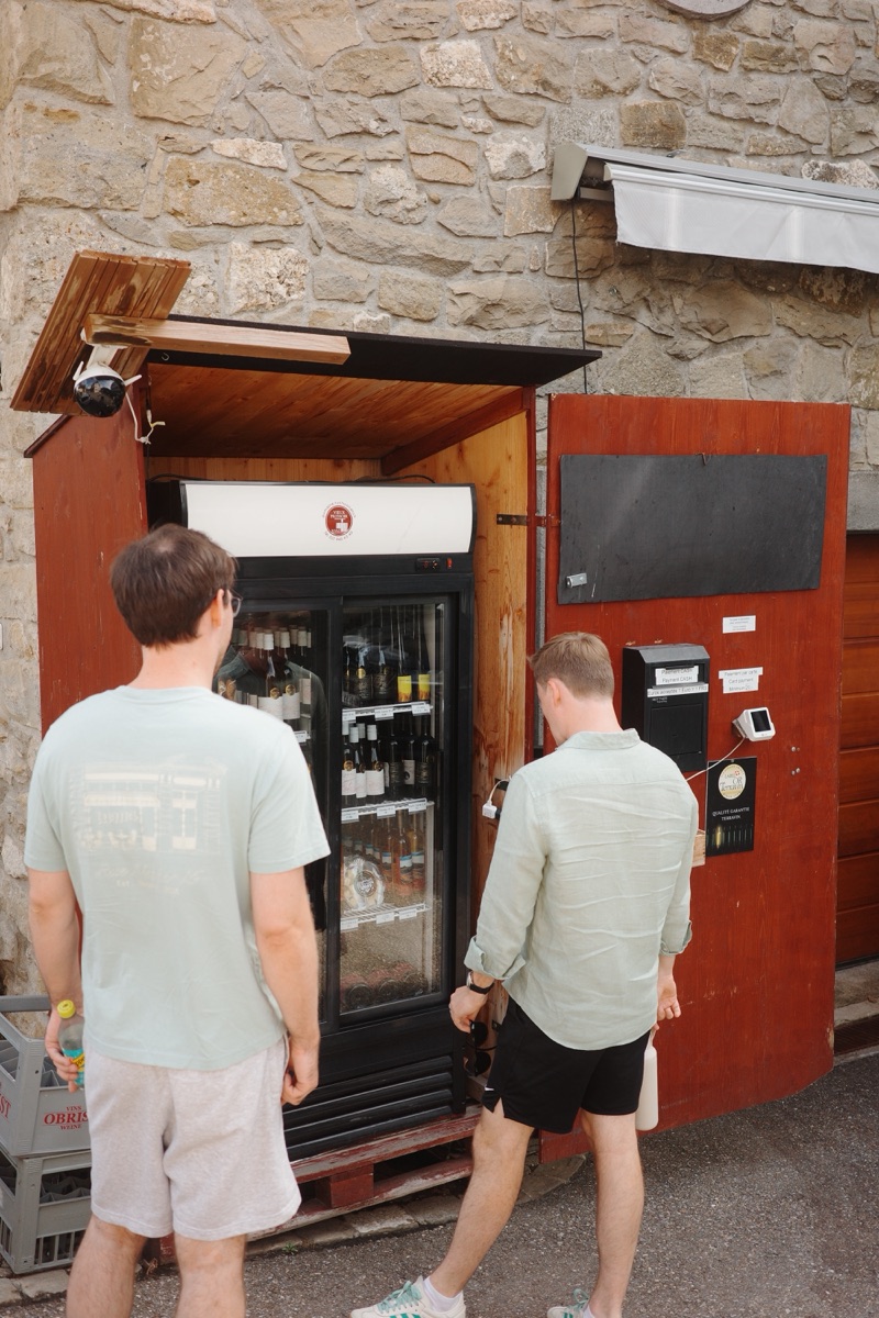 Two of us at a wine fridge built into a stone wall.